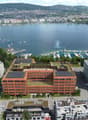 modern office building with solar panels, overlooking a large lake and a harbor