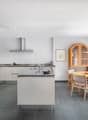 modern kitchen with island, fireplace, dining area, wooden table and chairs, glass door to garden