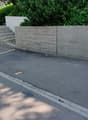 A grey concrete wall with steps, parked car, parking place, a blue cover over an object.