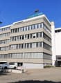 modern office building, multiple floors, glass windows, parking area in front