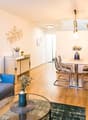 living room with wooden floor, blue couch, glass table, dining table and chairs, plants, wall decorations, lamps