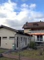 2 story house, brown roof, balcony, green trash bin, garden, fence