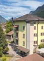 Mountain view residential area with several houses, brown roofs, yellow walls, small gardens, and nearby mountains