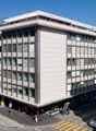 A building with multiple floors, several windows and multiple signs such as Helvetia and Allianz