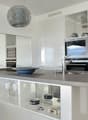 Modern kitchen with stainless steel appliances, granite countertops, white cabinetry, center island, pendant lighting, mirror wall