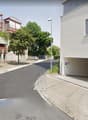 Building facade, visible parking area, garage entrance, streetlight, cars parked on the side.