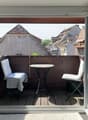 Balcony with table and chairs, wooden floor, open sliding doors, view of the city