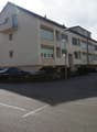 multi-family house, beige facade, balcony on the 2nd floor, street with parked cars