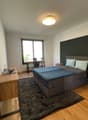 bedroom with bed, desk, chair, radiator, window, rug, lamp, nightstands, flowers