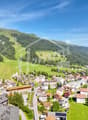 Mountain village with houses, green fields, and mountains in the background