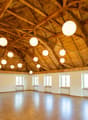 large open space, wooden floor, wooden ceiling, hanging lamps, windows
