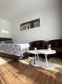 Bedroom with bed, 2 chairs, white table, white nightstand, lamp, carpet, picture on wall