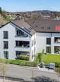 2 story house, white exterior, brown roof, multiple windows, balconies, solar panels, garden, driveway