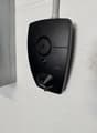 Black electric vehicle charger mounted on white wall, branded Zaptec