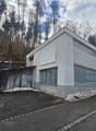 Modern building, white exterior, grey brick walls, glass windows, garage entrance, concrete walkway