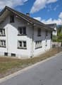 2 story house, white exterior, multiple windows, chimney, located on a street with mountains in the background