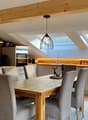 white kitchen, wooden floor, gray chairs, dining table, hanging lamp, kitchen appliances, two skylights