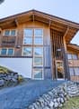 wooden exterior, large windows, stone wall, paved driveway, mountain view