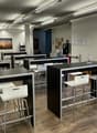 modern office room with black tables, white chairs, wooden floor, glass door, white walls, ceiling lights
