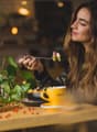 A table with food and drink, a woman eating with a fork