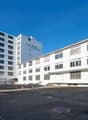 Two white multi-story buildings with large windows, a paved parking lot, and street lighting.