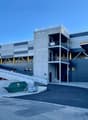A multi-story commercial building with a gray and blue exterior. The building has a large garage door and a dumpster in the foreground, indicating it is likely a storage or warehouse facility.