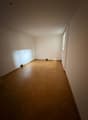 an empty room with wooden floor, white walls, and a window