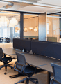 Open office with multiple cubicles, desk, chairs, glass partition walls, lamps, carpet
