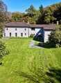 villa with garden, paved driveway, brown roof, surrounded by trees and mountains