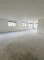Empty room with white walls, concrete floor, and windows with blinds