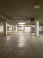 Underground parking lot, concrete floor, white walls, ceiling lights, yellow parking lines, entrance on the right