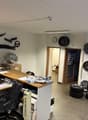 An office with a desk, chairs, computer monitors, a clock, tires, and wheels displayed on the walls.