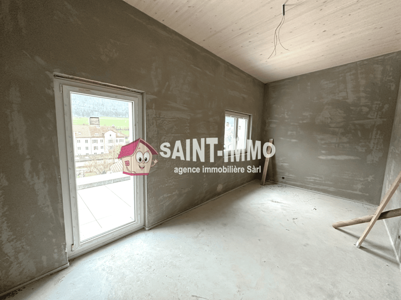Unfinished room with concrete walls, windows, and a Saint-Immo real estate agency logo on the wall.