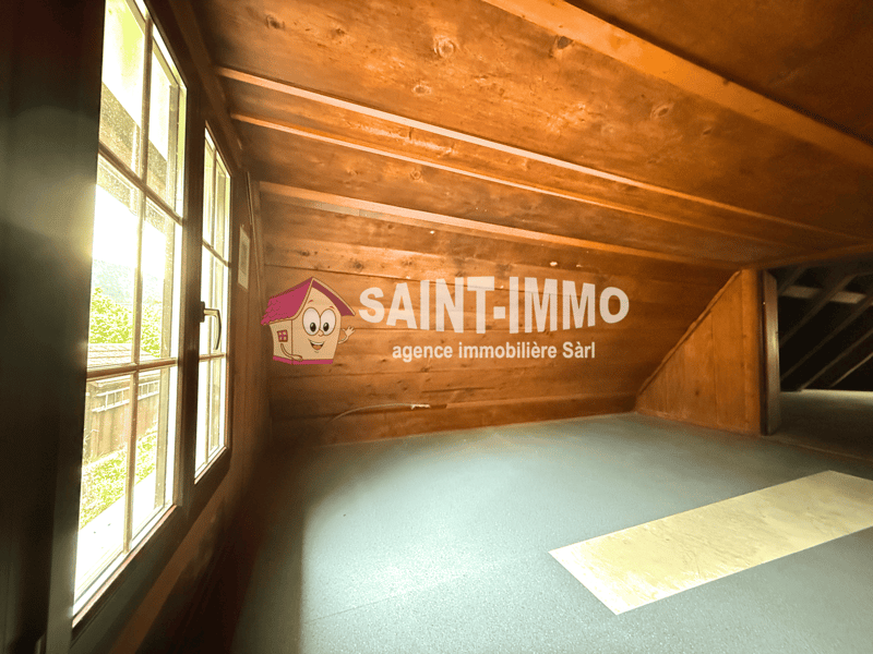 Attic room with wooden walls, windows, and a covered floor area