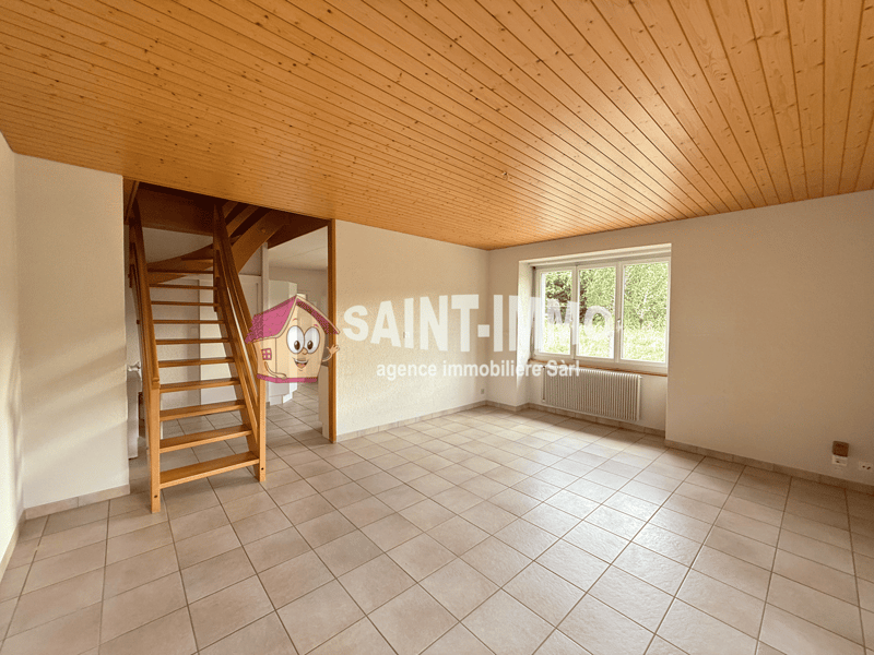 Empty room, wooden ceiling, tiled floor, white walls, window, radiator, wooden staircase.