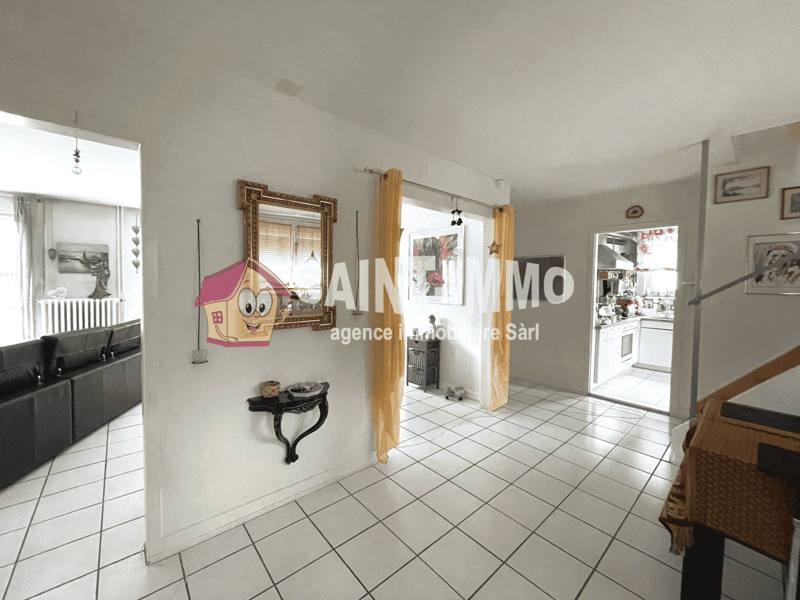 White tiled floor, yellow curtains, mirror, black couch, decorative items, photos on wall, stairs leading up