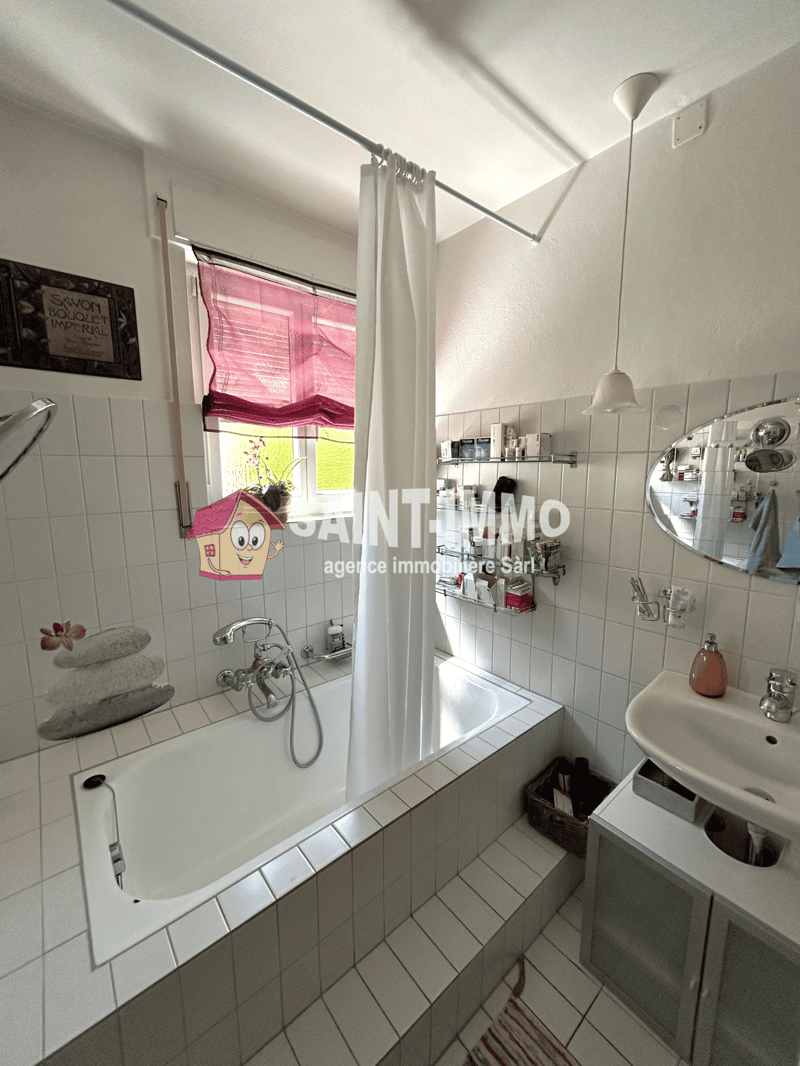 Tiled bathroom with a bathtub, sink, and washing machine. The room has white walls and a pink curtain on the window.