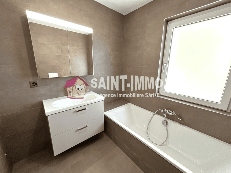 Spacious bathroom with beige tile walls, a white vanity with drawers, a large mirror, and a bathtub.