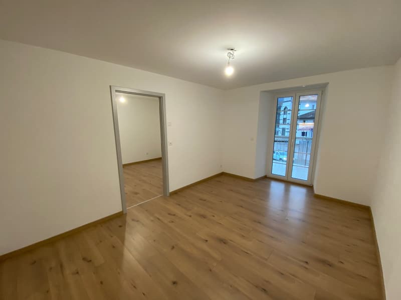 empty room with balcony, hardwood floors, white walls, and glass door