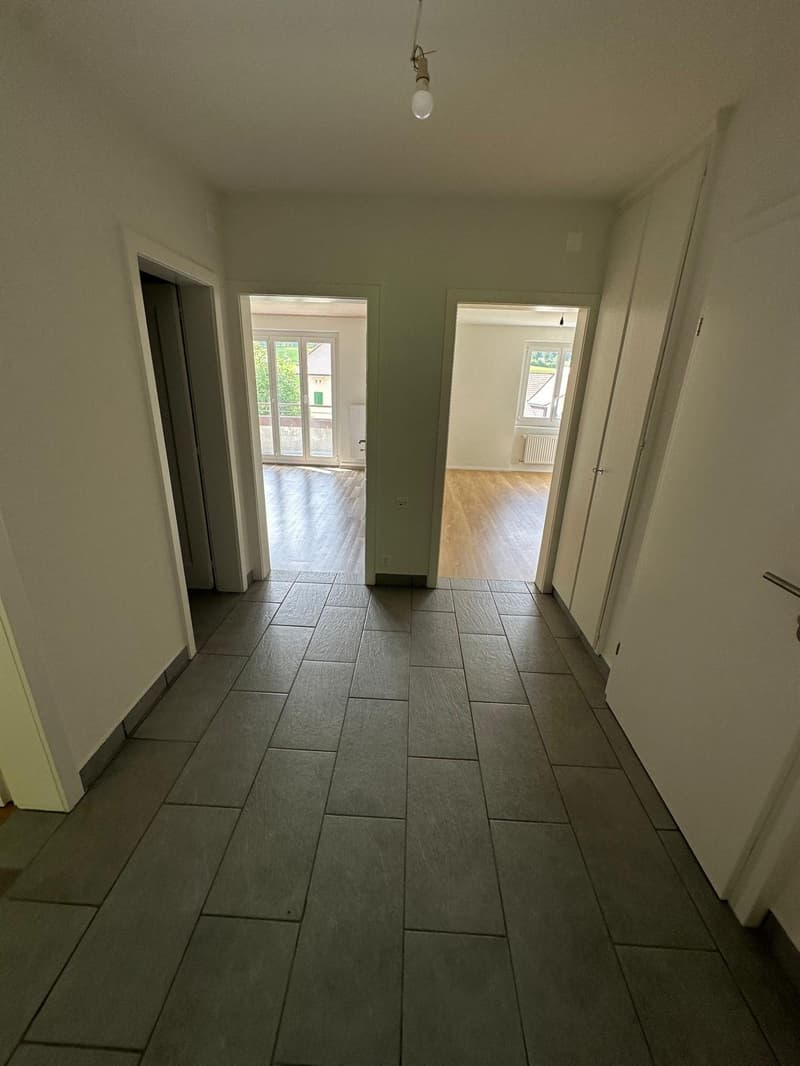 Empty hallway with tiled floor, white walls, and doors leading to different rooms.