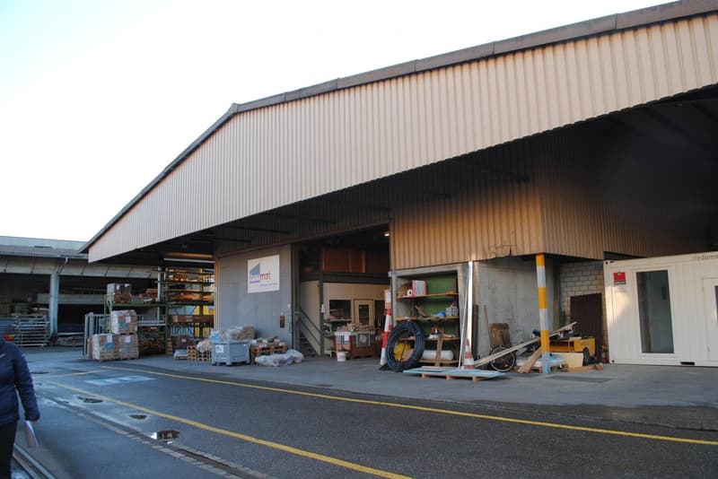 Industrial building with a sign reading 'Baumat', large storage area, various items and vehicles inside