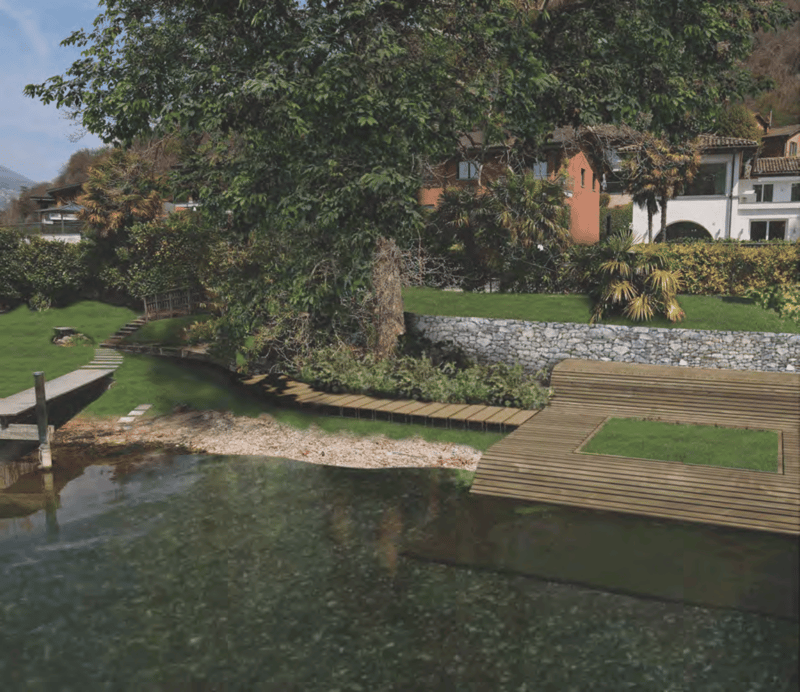 Lush green garden with a pond, wooden walkway, and stone walls. The garden is surrounded by trees and vegetation, creating a serene and peaceful environment.