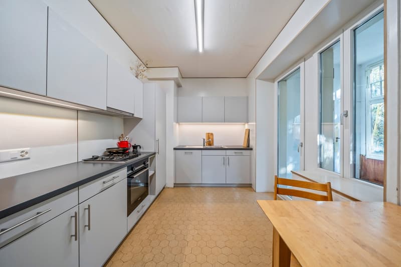 Modern kitchen with white cabinetry, granite countertops, integrated stove, oven, and sink.