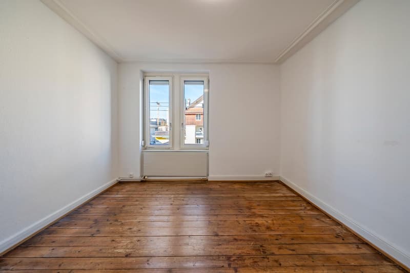 empty room with wooden floor, white walls, white radiator, window