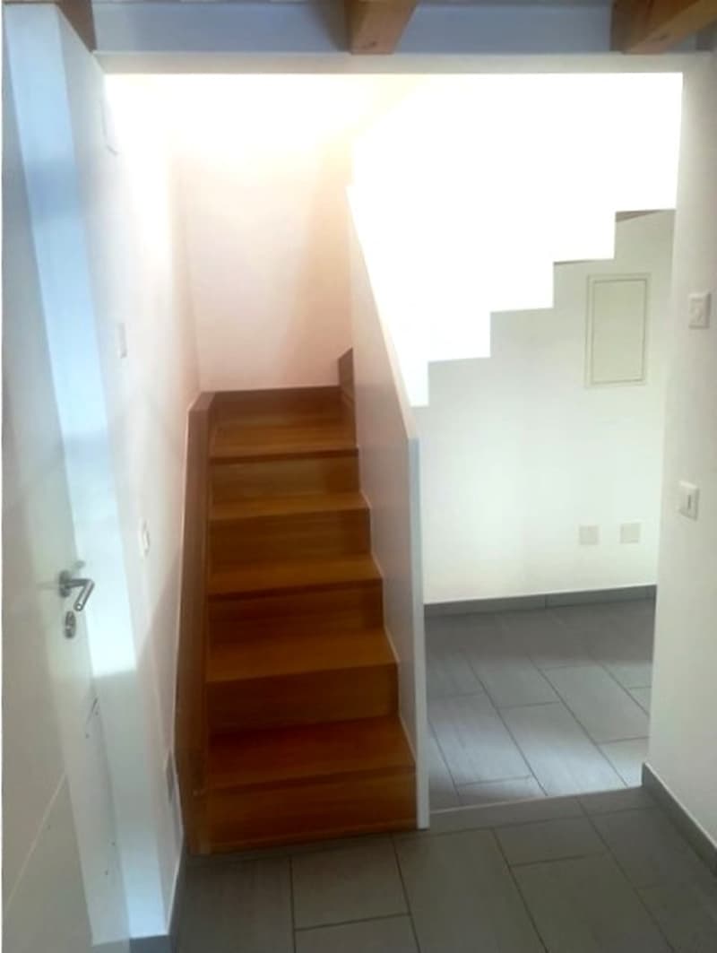 wooden stairs, white walls, tile flooring, light coming from above