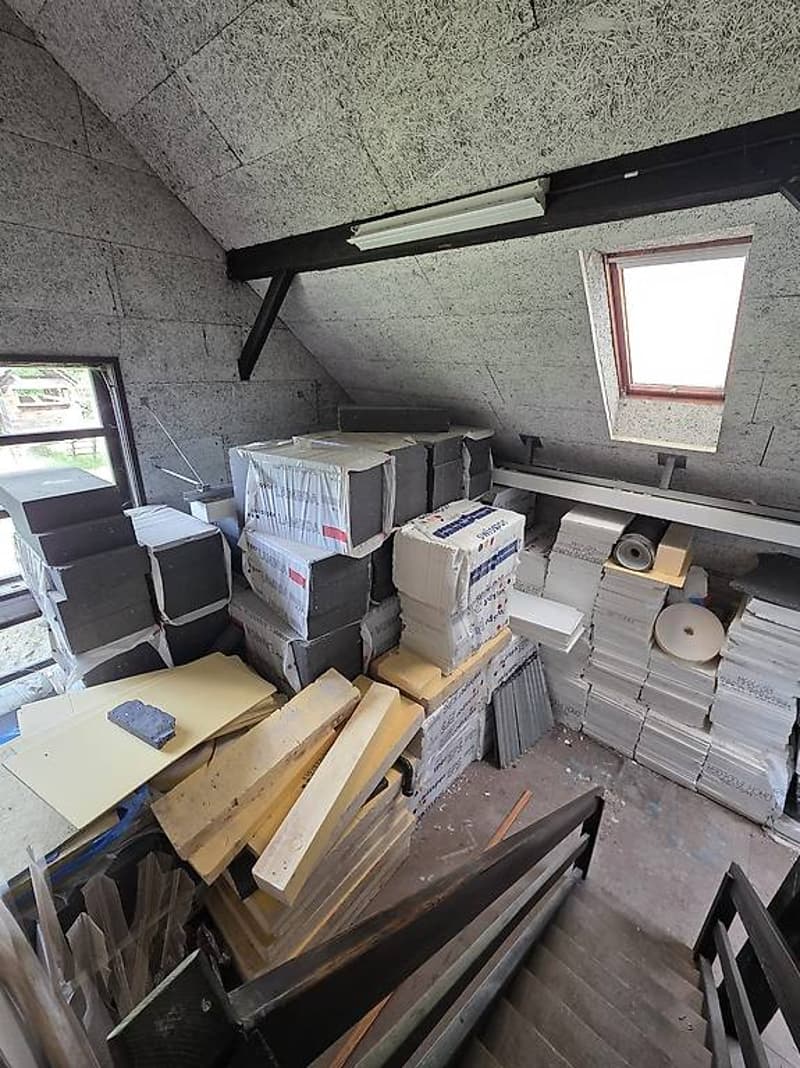 a storage room with materials, boxes, wooden planks, and a small staircase