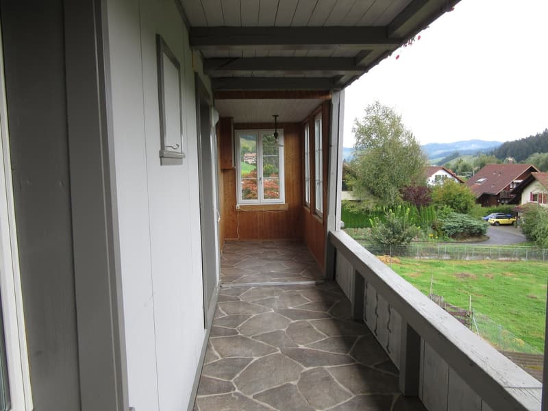balcony with stone floor, wooden walls, white railings, windows, lamp