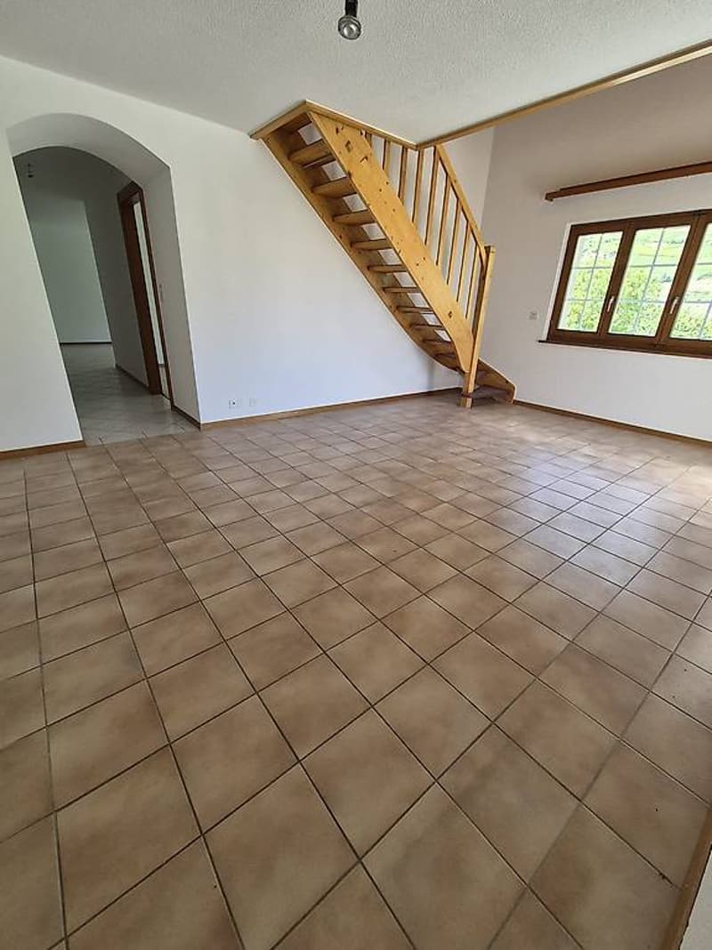 large room with tiled flooring, wooden staircase, arched doorway, windows