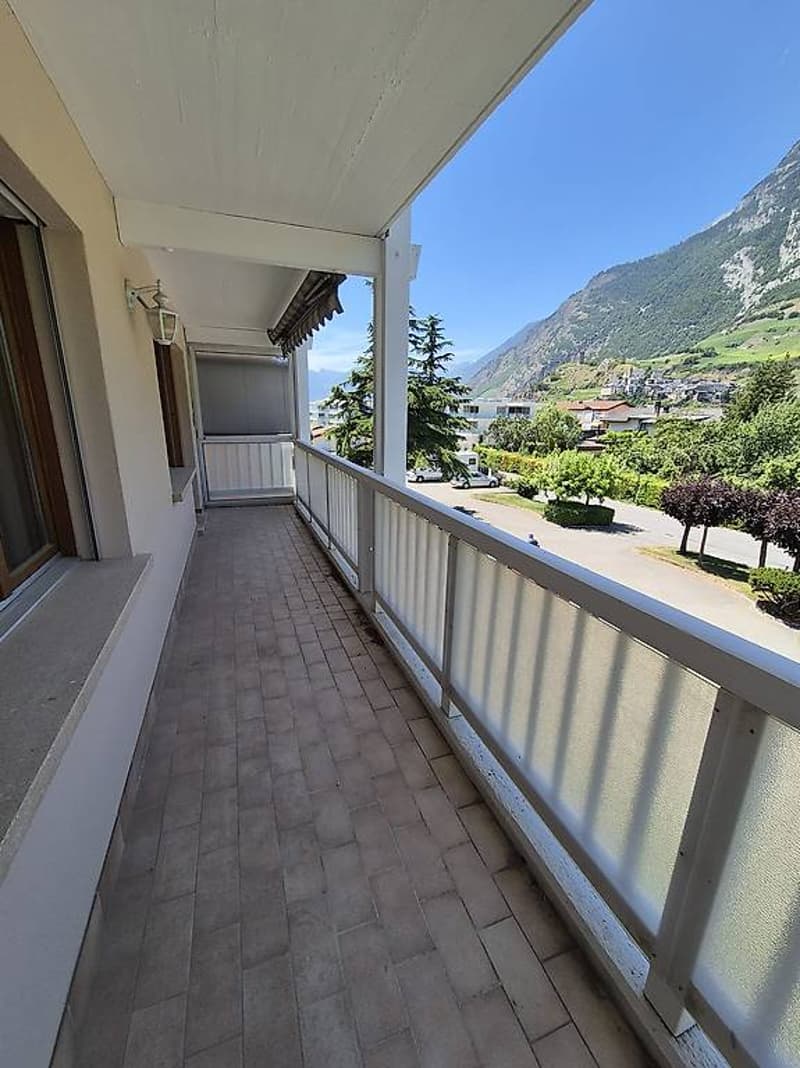 covered balcony with wooden tiles, glass barrier, street view, mountains view
