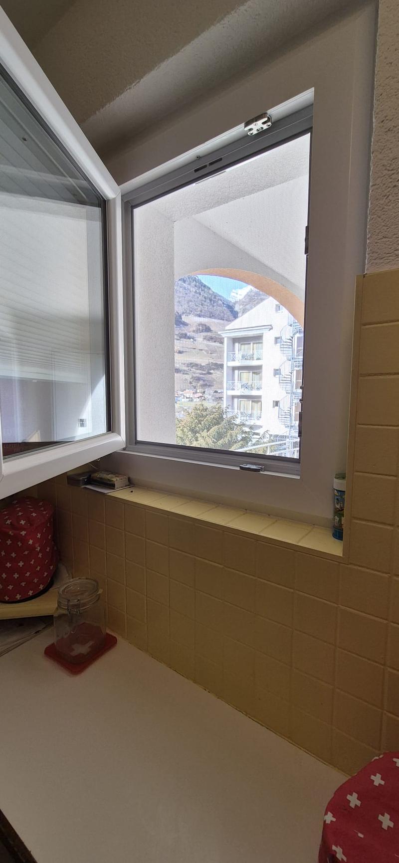 kitchen window with mountain view, tiles, white shelf, glass jar, red bag, bottle